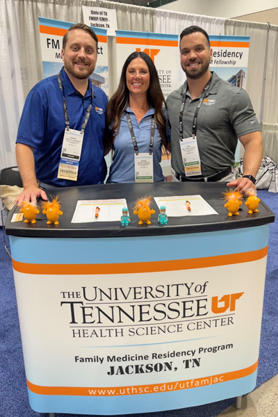 Three faculty members standing at the UTHSC booth