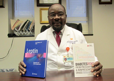Dr. Dagogo-Jack sitting at a desk holding two of his recently published books