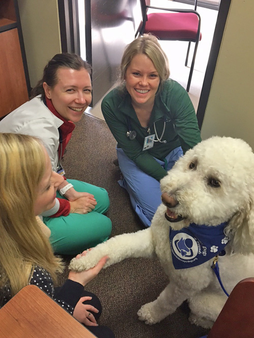 Three female residents with a white therapy dog