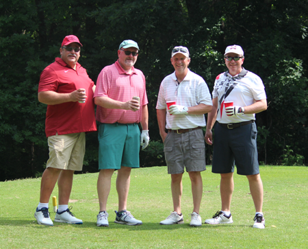Four faculty standing on the golf course