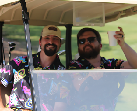 Two male residents driving a golf cart