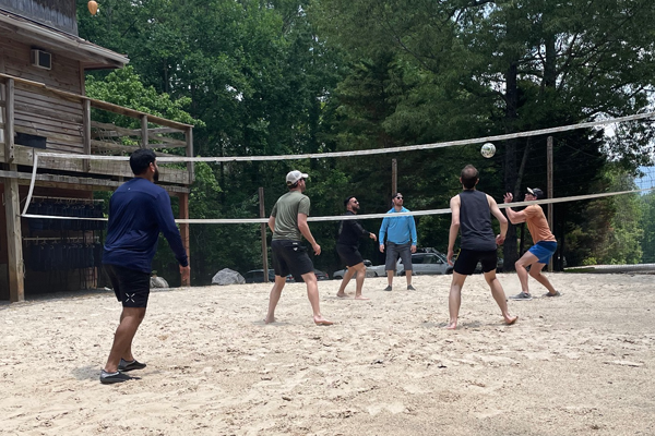residents playing volleyball in the sand outside