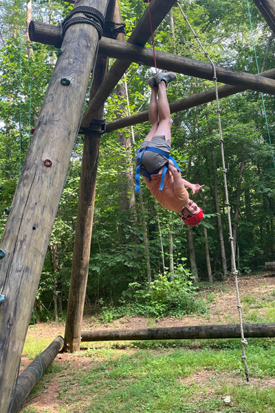 Resident hanging upside down on a ropes course