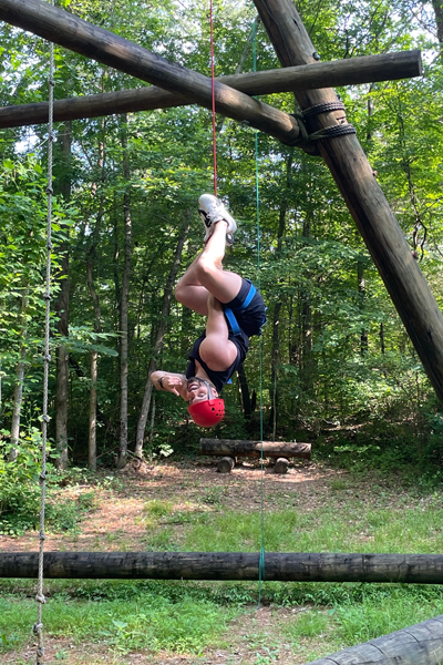 Resident hanging upside down on a ropes course