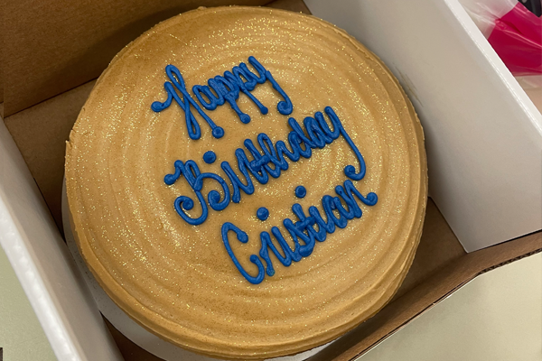 Resident's gold birthday cake with blue writing in a box