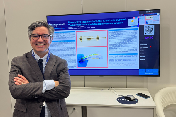 Resident in front of a poster presentation at a conference