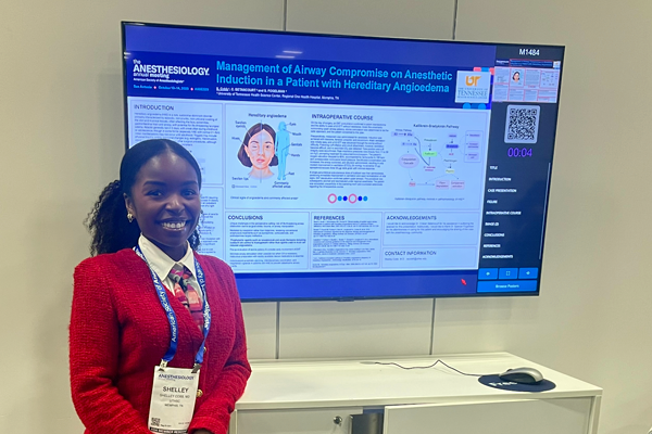 Resident in front of a poster presentation at a conference