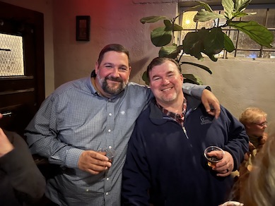 Two happy male faculty at the holiday party