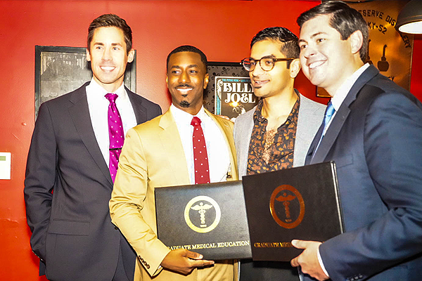 Faculty standing with graduates holding a certificate