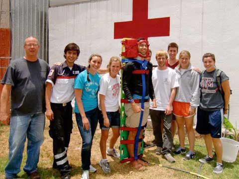 CIAO students in front of a wall with a red cross on it