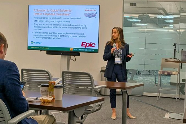 Faculty speaking before a large screen in a classroom setting