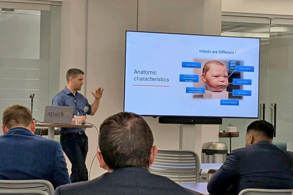 Faculty speaking before a large screen in a classroom setting