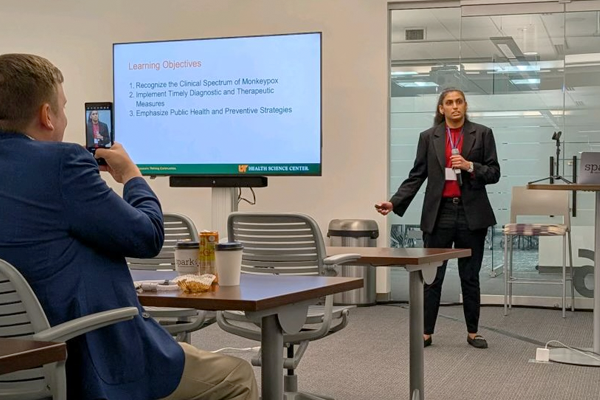 Faculty speaking before a large screen in a classroom setting