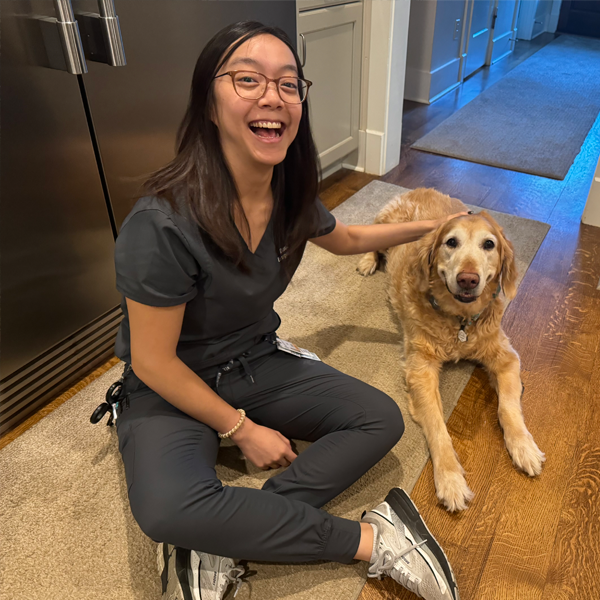 Female resident sitting on the floor, petting a blonde dog