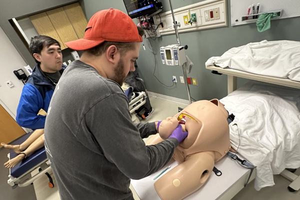 Resident working on a dummy patient in a clinical setting