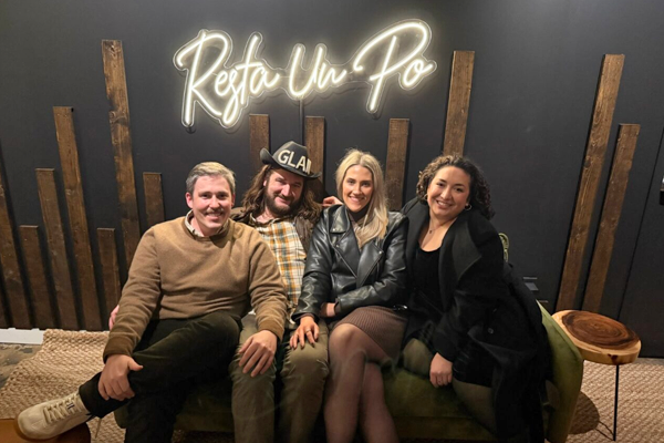 Residents inside sitting on a sofa in front of a resta un po neon sign