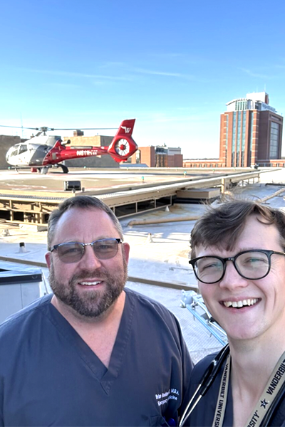 Faculty member and program manager on the roof with a helicopter in the background