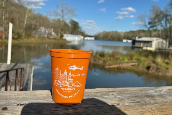 Orange emergency medicine cup sitting by a lake on a dock