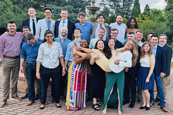 Group of residents outside with three female residents holding up another female resident