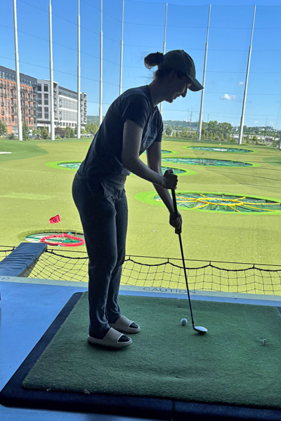 Female resident with a golf club about to drive a golf ball