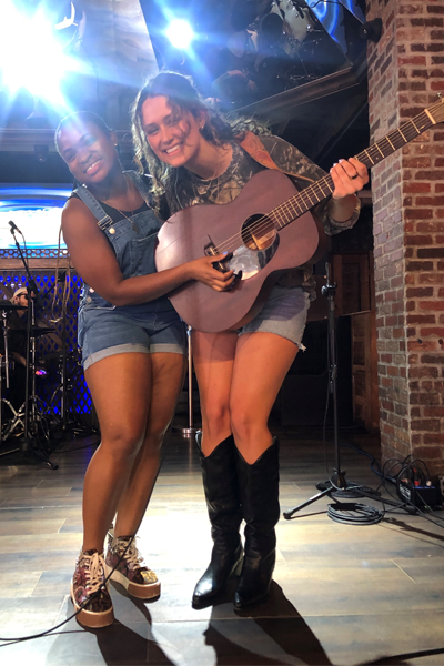 Two female residents on stage with on holding a guitar