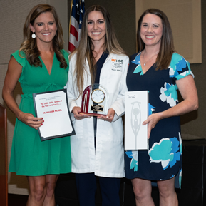 Three female residents holding awards and certificates