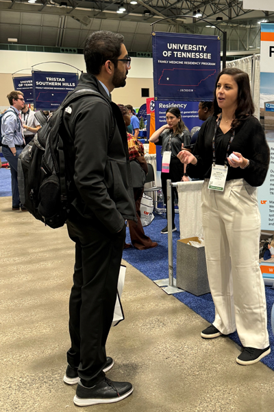 Resident talking to someone at the booth on the conference floor