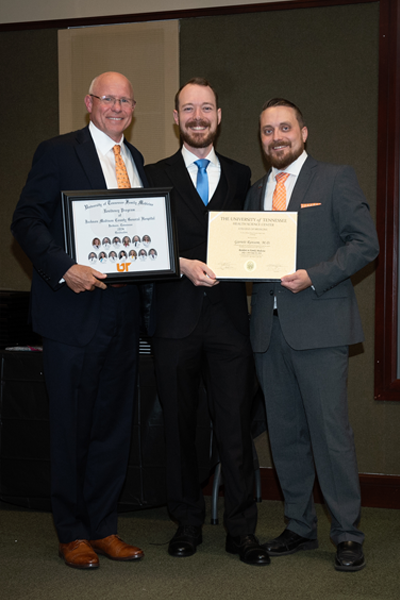 Faculty standing with a resident holding a certificate