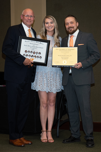 Faculty standing with a resident holding a certificate