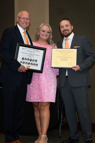 Faculty standing with a resident holding a certificate