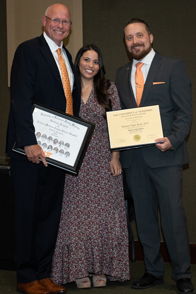 Faculty standing with a resident holding a certificate