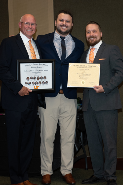 Faculty standing with a resident holding a certificate