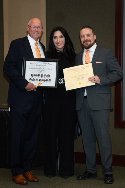 Faculty standing with a resident holding a certificate