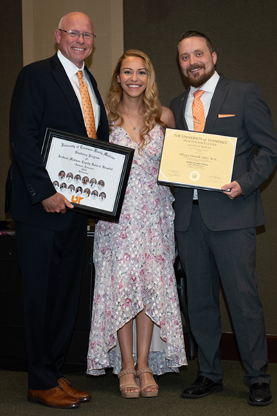 Faculty standing with a resident holding a certificate