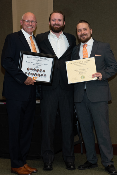 Faculty standing with a resident holding a certificate