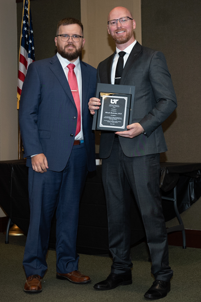 Faculty standing with a resident holding an award