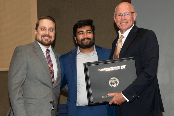 Resident holding a certificate with faculty at graduation