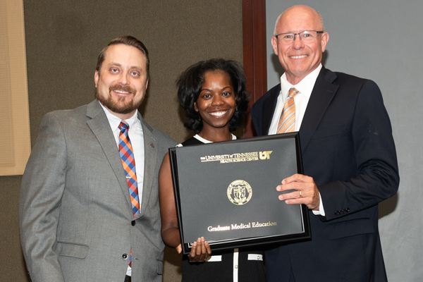 Resident holding a certificate with faculty at graduation
