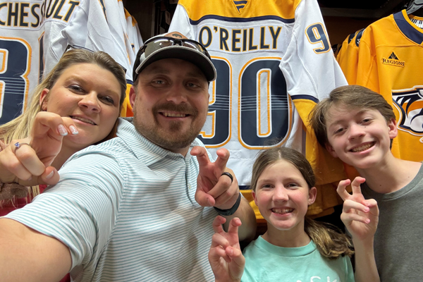 Program Director and family standing in front of Nashville Predator jerseys in a store