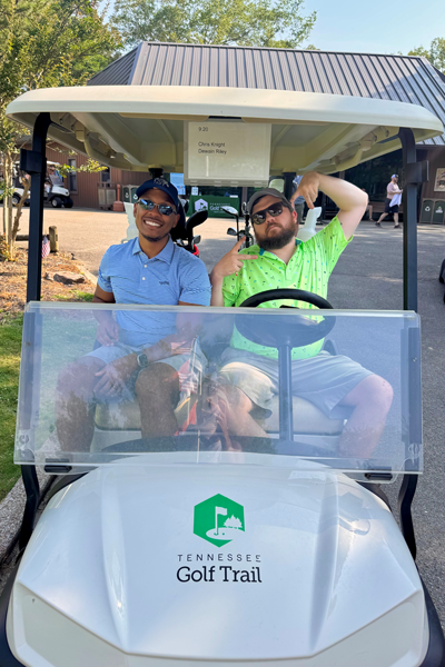 Two male residents sitting in a golf cart on the golf course