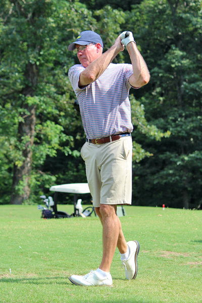 Male faculty member swinging a golf club on the course