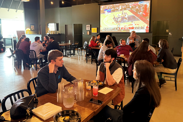Residents sitting a tables in a restaurant with a basketball game on the television