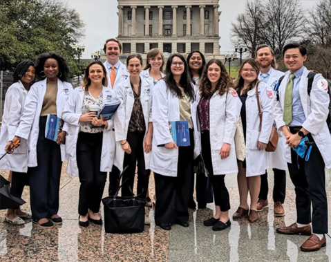 Residents in white coats in front of the state capital building