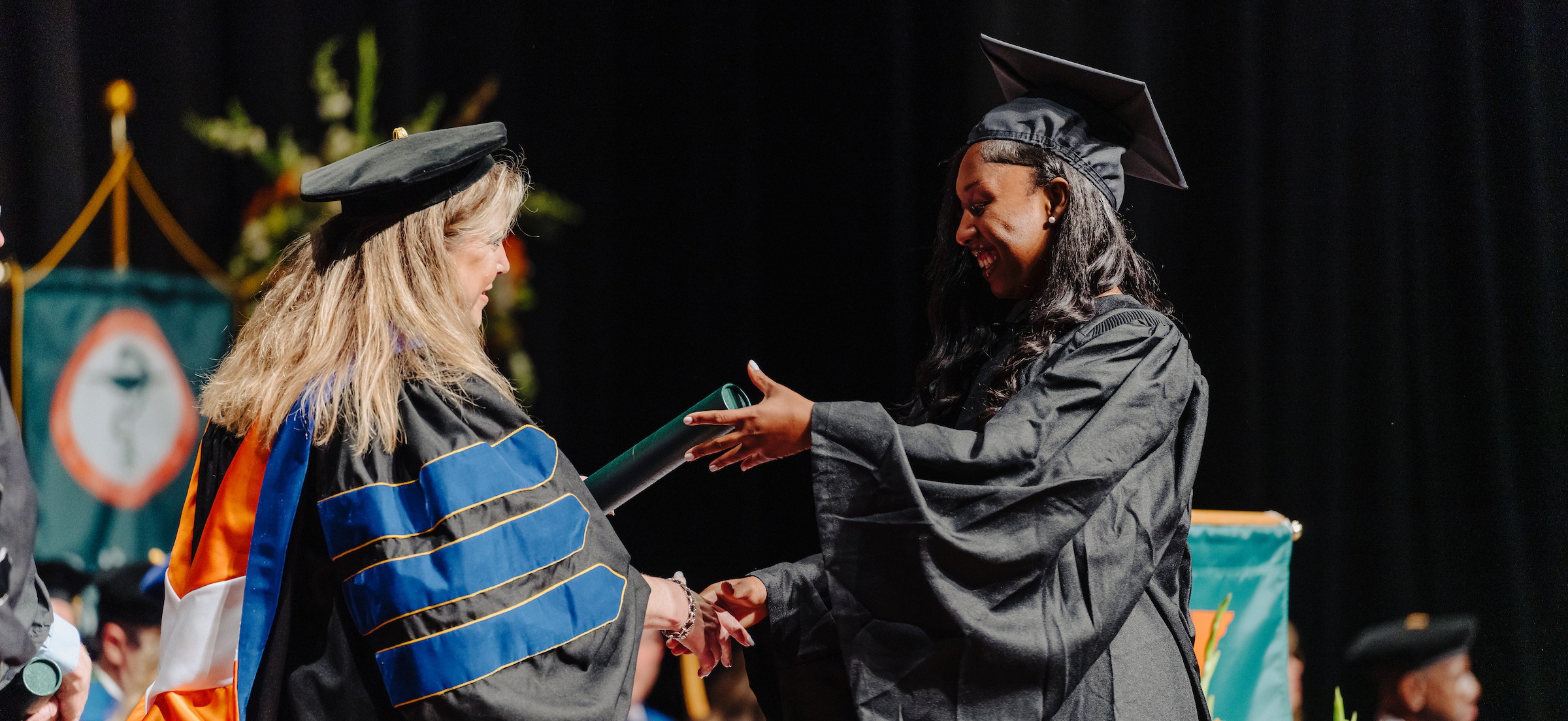 woman in graduation gown receiving nursing diploma