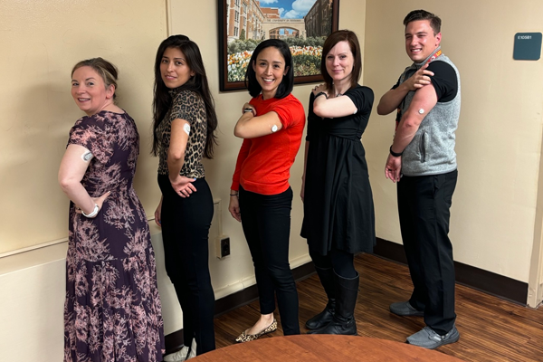 Group photo in an office setting with fellows showing shot cottonballs on their arms