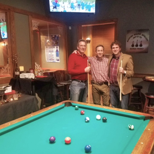 Fellows and faculty around a pool table