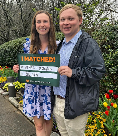 Future male and female residents in front of a flowery garden holding a UTHSC matched sign