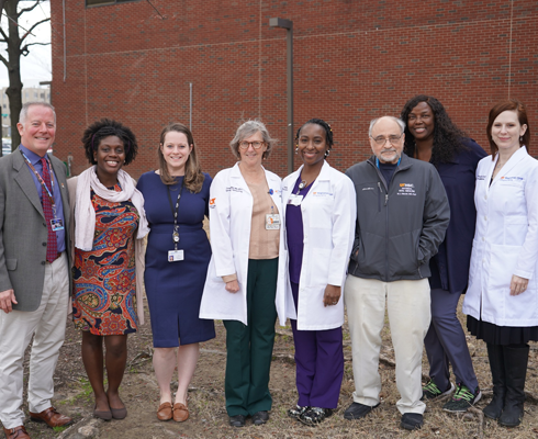 Faculty outside in front of a red brick building