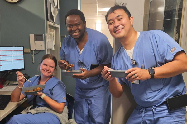 Residents wearing scrubs eating in an office setting