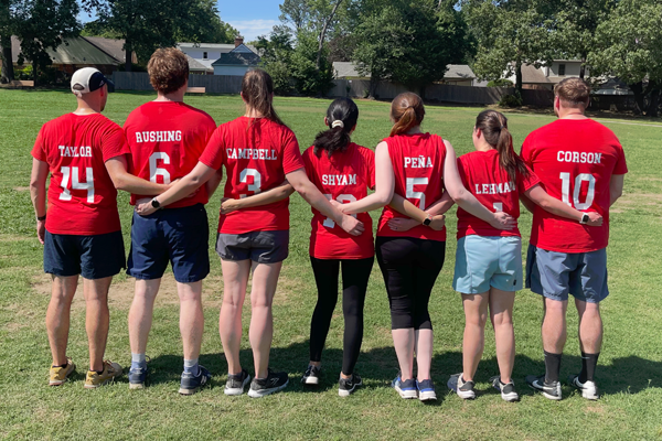 Fellows dressed in soccer gear with their arms around each other and backs to the camera